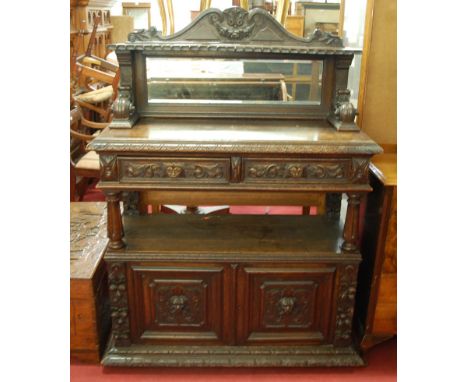 A late 19th century heavily carved oak mirror back buffet side cabinet, the raised superstructure with integral shelf over tw