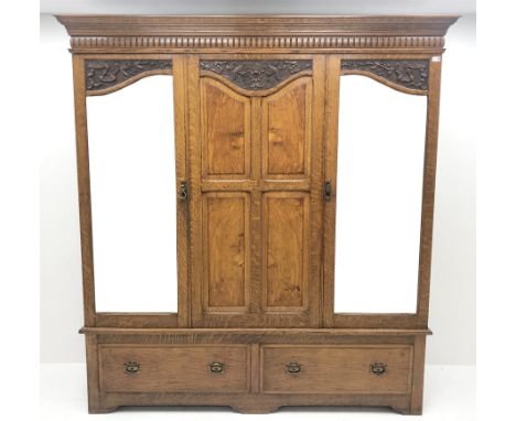 Early 20th century carved oak triple wardrobe, with two shaped mirrored doors, two drawers to base with Art Nouveau copper ha