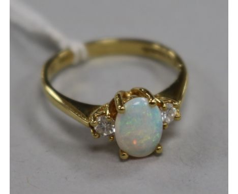 An opal and diamond three-stone ring, the opal flanked by two brilliants, 18ct gold setting, size O.