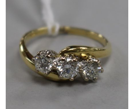 A modern 18ct gold and three stone diamond crossover ring, size R.