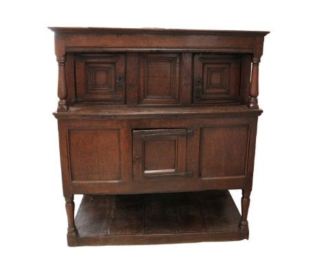 A MID 17TH CENTURY JOINED OAK LIVERY CUPBOARD the moulded cornice over a recessed upper cupboard, with moulded panel doors fl