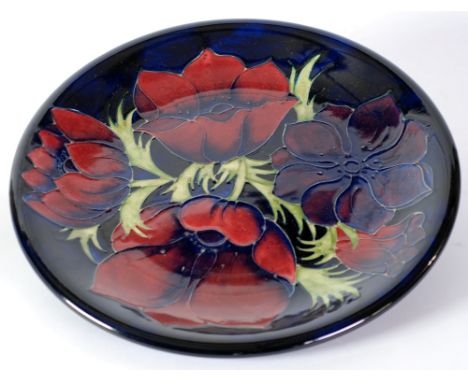MODERN MOORCROFT ANEMONE PATTERN TUBE LINED POTTERY WALL PLAQUE,  decorated in tones of red, blue and green on a dark blue gr