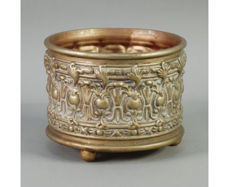 A CONTINENTAL GILDED TERRACOTTA FAUX STAMPED BRASS PLANTER moulded in relief with encircling stylized borders, on three ball 