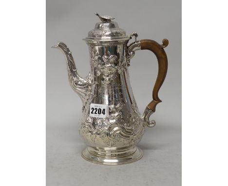 An early George III silver coffee pot of baluster form, later embossed and chased with floral and foliate scrolling decoratio