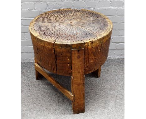 A 19th century oak tree trunk chopping block, with metal inset top on three block supports, 60cm diameter x 64cm high. 