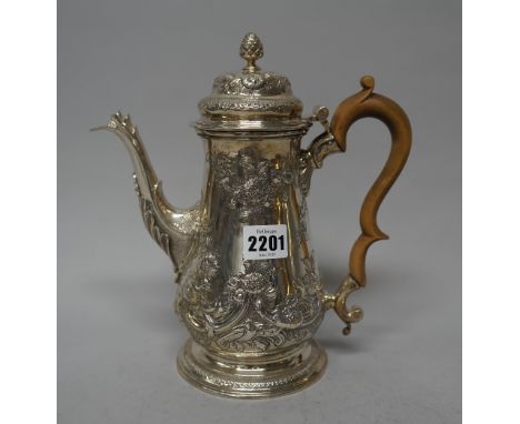 A late George II silver coffee pot, of baluster form, with floral, foliate and scroll embossed later decoration, crest engrav