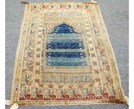 A Ghirodes prayer rug, Turkish, the plain banded indigo mehrab rising to a leaf filled arch; a plant border, 176cm x 121cm. 