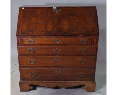 A late George III walnut and mixed wood bureau with fitted and welled interior, over four long graduated drawers on shaped br