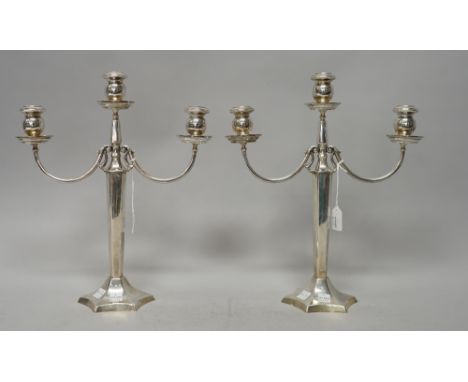 A pair of three light table candelabra, each with a curved arm, raised on a tapered hexagonal stem and on a swept hexafoil ba
