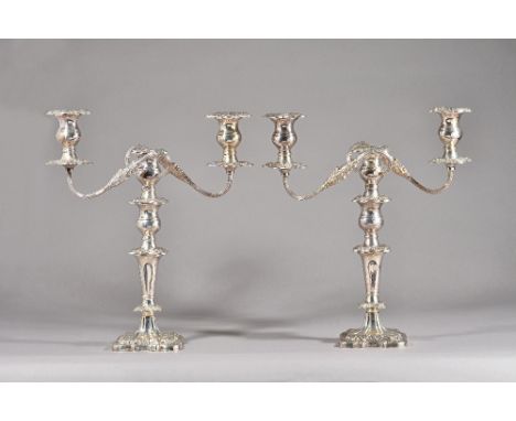A pair of silver three light table candelabra, each with scrolling fluted arms and on a shaped square base, with foliate and 