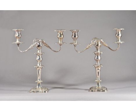 A pair of silver three light table candelabra, each with scrolling fluted arms and on a shaped square base, with foliate and 