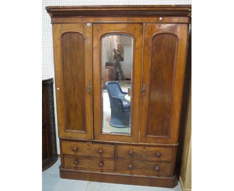 A Victorian mahogany triple wardrobe with mirrored door on plinth base. 