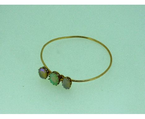 A graduated three stone opal Bangle, the stones claw set on a yellow metal bar, on a rose coloured 'wire' bangle, central opa