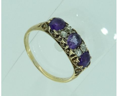 A graduated three stone amethyst Ring, with two small diamonds between, in a carved gallery and shank in 18ct yellow gold, Si