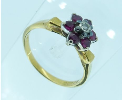 A small ruby and diamond flower head Ring, the diamond point surrounded by six pale rubies, mounted in yellow gold marked 750