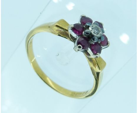 A small ruby and diamond flower head Ring, the diamond point surrounded by six pale rubies, mounted in yellow gold marked 750