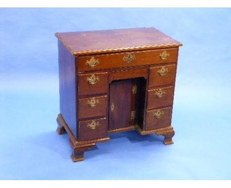 A George III mahogany kneehole Desk, the rectangular top with moulded edge above a frieze drawer, kneehole cupboard flanked b