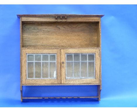 A Harris Lebus style oak hanging Smoker's Cabinet, decorated with bands of inlaid decoration, the shaped top above an open sh