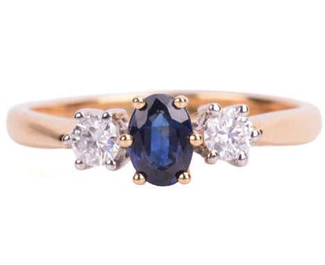 A sapphire and diamond trilogy ring in 18ct bi-coloured gold, centred with an oval-cut sapphire of dark blue colour, approxim