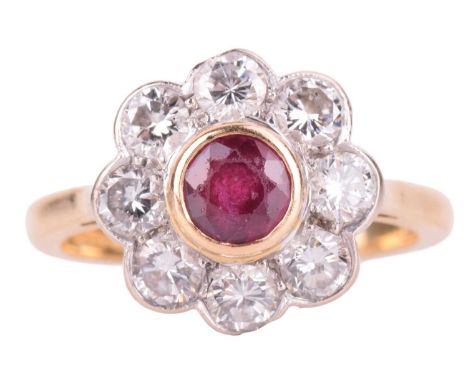 A ruby and diamond cluster ring set in 18ct gold, the round central ruby measuring approximately 4.5mm and surrounded by eigh