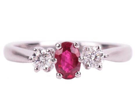 A ruby and diamond trilogy ring in 18ct white gold, centred with an oval-cut ruby of purplish-red colour, approximately measu