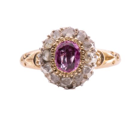 A pink sapphire and diamond set cluster ring, with an oval mixed cut pink sapphire measuring approximately 5mm x 4mm surround