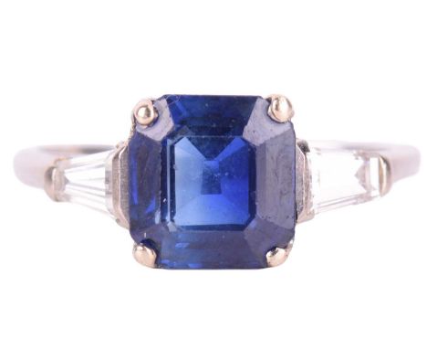 A sapphire and diamond three-stone ring, featuring a central octagonal step-cut sapphire, flanked by tapered baguette cut dia