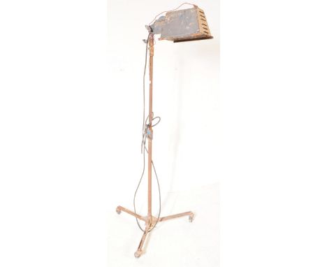 A vintage mid 20th century industrial floor standing spotlight lamp. The lamp raised on a cast metal base with three splayed 