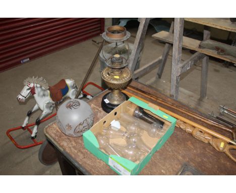 A brass oil lamp, various glass chimneys and an ornate glass lampshade 