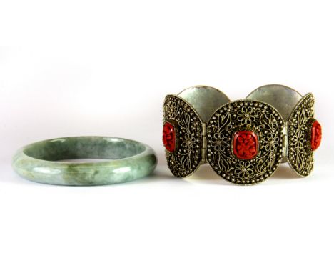 A Chinese hinged white metal and cinnabar bracelet together with a jade bangle.