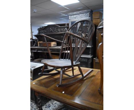 A dark stained Ercol rocking chair having fluer de lys style back