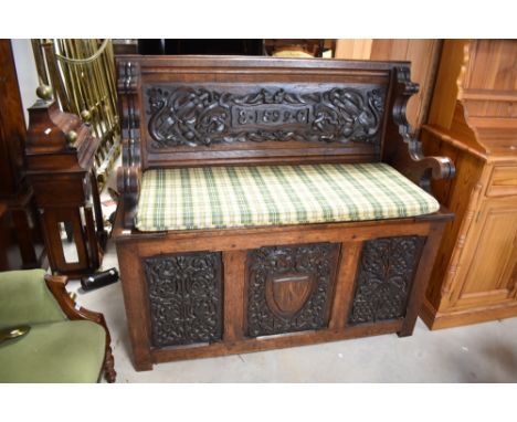 A 19th Century carved oak monks bench, heavily carved including dragons, monogram EC and 1899