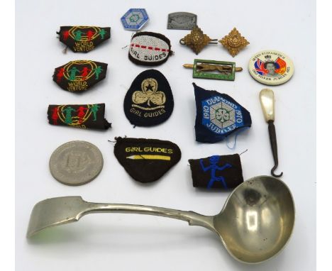 A selection of girl guide badges twinned with a  'Bombay Silver' ladle, military buttons, a crown & a mother of pearl mounted