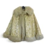 A cream and gilt brocade fur trimmed cape, by Woolright & Co., Liverpool, with turn up collar, satin