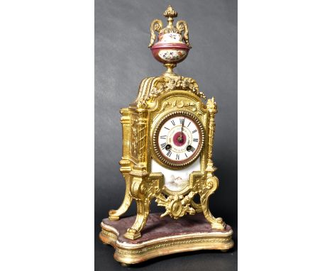 A 19th Century French ormolu clock on stand having a hand painted urn finial atop with gilt mounts over a circular enamel dia