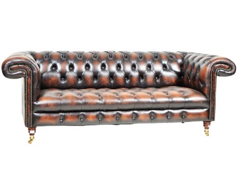 A contemporary Chesterfield manner dark brown leather three seater sofa settee having scrolled button back backrest and arms 