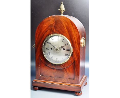 An early 19th Century Regency mahogany mantel bracket clock having an alarm setting. The clock of arched shape having a flame
