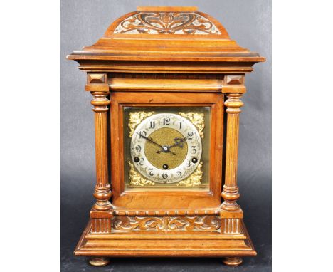 A 19th Century German carved walnut cased mantel / bracket clock having an arched top section with carved scrolls and central