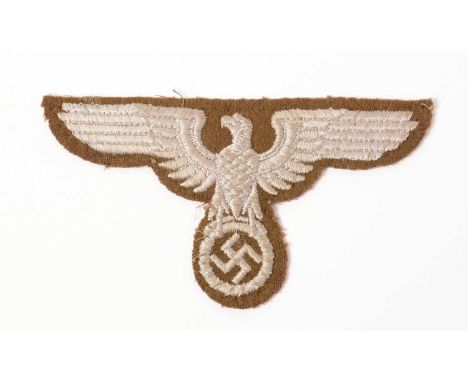 A WWII German Eastern People's sleeve eagle, in silver threads with eagle surmounting a wreathed swastika, on brown backing, 