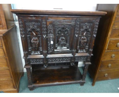 A small heavily carved Carolean style stained oak court cupboard with three medieval ecclesiastical and court figures to the 