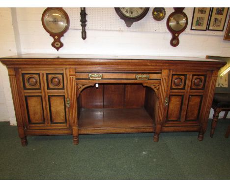 A long burr oak Edwardian sideboard with two side cupboards and central long drawer with an open shelf beneath, the panels ha