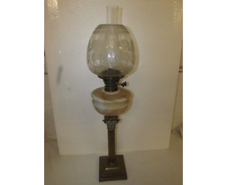 A Victorian oil lamp with a Corinthian brass column on a square base, with a marbled milk glass reservoir and an etched glass