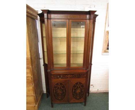 An elegant Edwardian display cabinet decorated with foliate inlay and ebony and boxwood stringing, the upper section glazed t