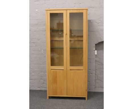 A modern carved light oak display cabinet over cupboard base, 180cm high, 81cm wide, 39cm depth.