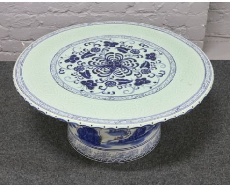 A Chinese blue and white ceramic table top with floral decoration on associated base.