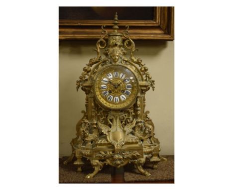 Early 20th Century cast brass cased mantel clock elaborately decorated with gryphon, mask heads and scrolling foliage movemen