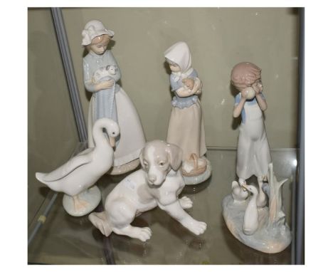 Group of five Nao Spanish porcelain figurines comprising: two young girls, each with puppy, figure of a seated dog, figure of