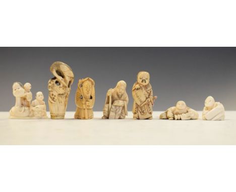 Group of seven Japanese late Meiji period carved ivory netsuke to include; a figure group holding theatre masks, figure holdi