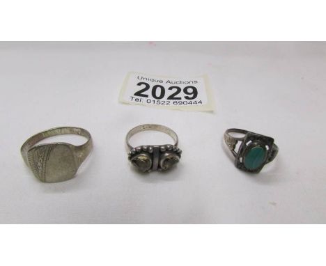 A silver signet ring and two other silver rings.