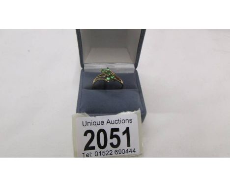 A 9ct gold ring set green stones, size T.